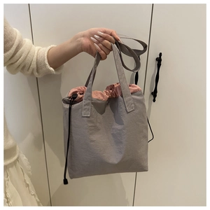 Detail of gray drawstring tote bag showing pink lining and black adjustable buckle
