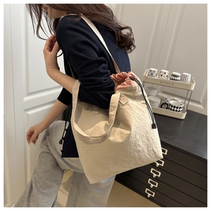 Close-up of beige textured tote bag with pink drawstring interior on a female model