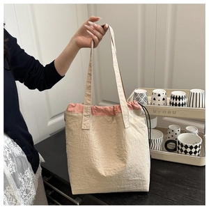 Close-up of beige drawstring tote bag with pink trim and crinkled texture fabric