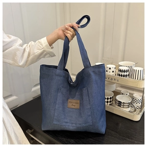 Détail du grand sac cabas en denim bleu marine avec étiquette logo en cuir mode