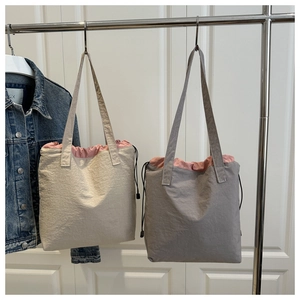 Detail showing casual nylon tote bags in beige and grey with contrast pink lining