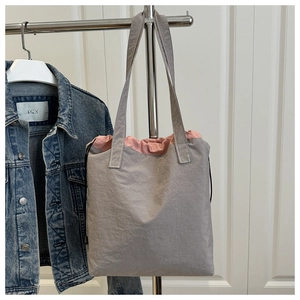 Detail of grey nylon tote bag with pink drawstring closure and adjustable shoulder strap