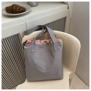 Detail of grey nylon tote bag with pink drawstring closure and contrast stitching