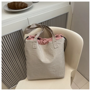 Detail of beige drawstring tote bag with pink lining and textured pleated fabric