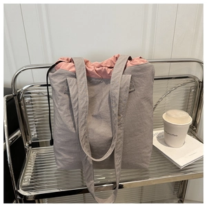 Detail of grey tote bag with pink drawstring closure and smooth nylon fabric texture