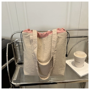 Detail of beige tote bag featuring pink drawstring lining and dual shoulder straps