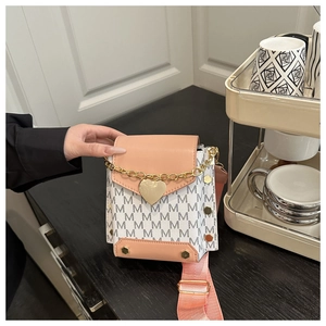 Detalle de bolso para móvil con estampado de monograma y colgante de corazón