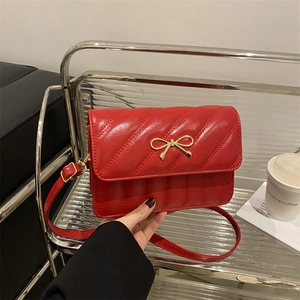 Red quilted crossbody bag with gold bow accent and elegant faux leather finish