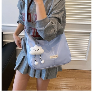 Detailopname van een blauwe draagtas met een witte pluche wolk smiley bedelaccessoire