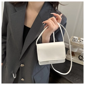 Detailed view of a white mini PU leather shoulder bag with fine stitching on model