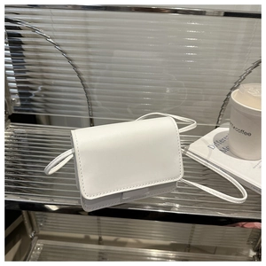 Detailed view of a white mini faux leather crossbody bag for girls on a stylish shelf