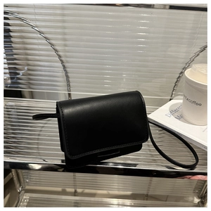 Close-up of minimalist black leather crossbody bag with refined stitching detail
