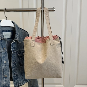 Minimalist beige drawstring tote bag with pink lining and adjustable side straps