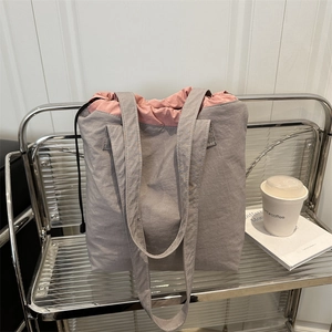 Minimalist grey drawstring tote bag with pink interior on a stylish silver metal shelf