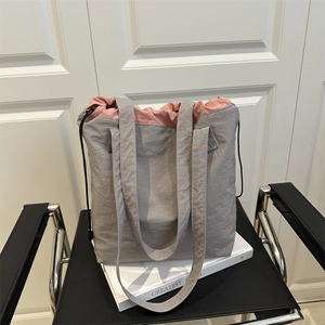 Minimalist grey nylon tote bag with pink drawstring lining and wide shoulder straps