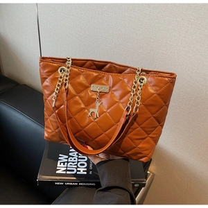 Detail of brown quilted faux leather tote bag with gold chain strap and deer charm