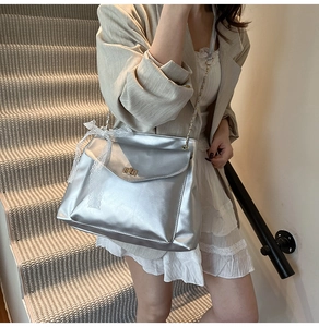 Close-up of silver chain tote bag with lace bow and golden clasp on model