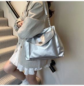 Detailed shot of silver metallic shoulder bag with gold twist lock and lace ribbon detail
