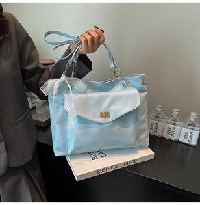 Detail of light blue tote bag featuring a white lace bow and gold metal buckle