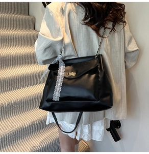 Detail of black PU leather shoulder bag featuring a lace bow and gold metal twist lock