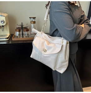 Close-up of cream shoulder bag featuring a gold twist lock and a white lace bow detail