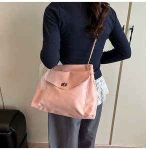 Detail of pink oversized tote bag featuring a gold twist lock and elegant chain strap