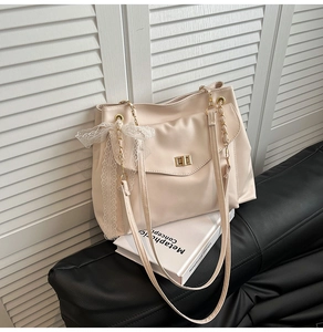 Detail of cream PU leather tote bag with lace bow decoration and gold chain strap