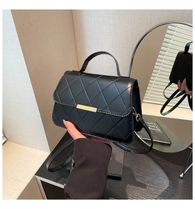 Detail of black quilted leather shoulder bag with gold metal clasp and top handle