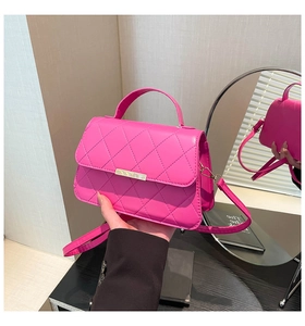 Detail of fuchsia quilted handbag featuring a gold buckle and elegant top handle