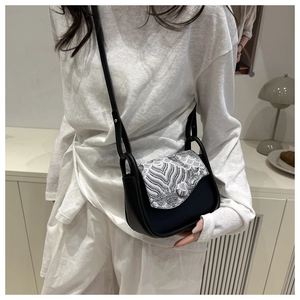 Detalle del bolso bandolera minimalista con elegante bordado de patrón de olas en blanco y negro