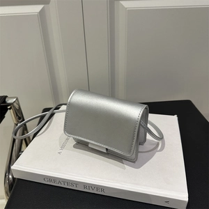 Sleek metallic silver mini crossbody bag for girls with thin shoulder strap on white books