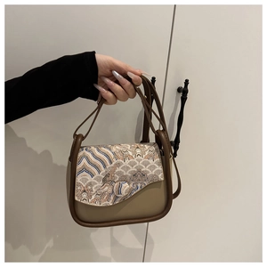 Detalle de bordado de olas vintage y asa marrón en bolso bandolera beige