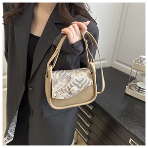 Primer plano del bolso de cuero caqui con bordado detallado de patrones de ondas orientales