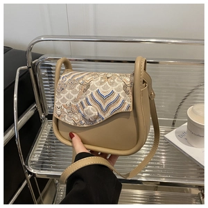 Detalle de bolso bandolera beige con bordado floral vintage y cuero sintético liso