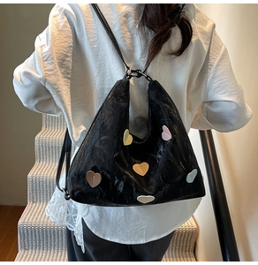 Detail of wrinkled black texture and colorful heart-shaped patches on multifunctional bag