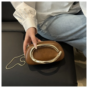 Close-up of brown leather evening clutch with a bold gold ring handle and snake chain