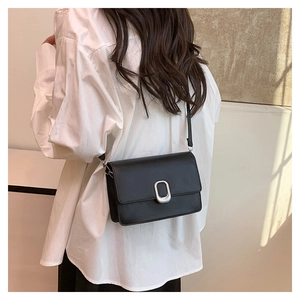 Detail of minimalist black crossbody bag with matte finish and silver rectangular buckle