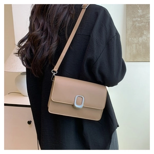 Detail of minimalist beige square bag with silver oval buckle and smooth leather finish
