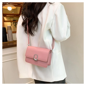 Rear view of a model wearing a pink crossbody square bag with silver metal buckle detail