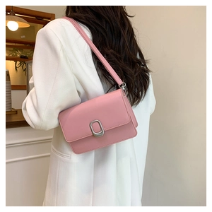 Detailed view of pink leather crossbody square bag worn on shoulder by a model