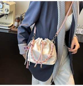 Fashionable color-block bucket bag with pink woven handle and drawstring closure