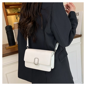 White minimalist leather square crossbody bag with silver buckle worn on person