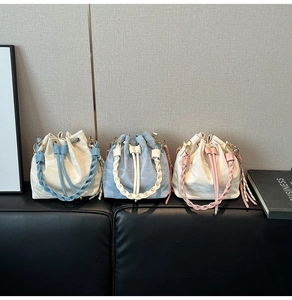 Three large woven bucket bags in cream, blue, and pink with braided handles and drawstring
