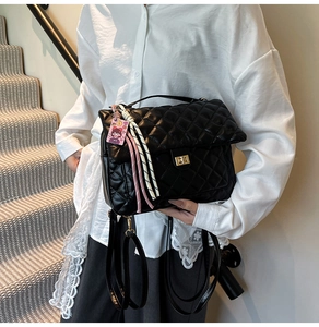 Close-up of black quilted PU tote bag featuring a gold twist-lock and decorative charm