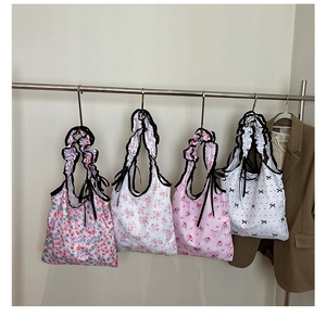 Detail of four floral canvas tote bags with ruffle edges hanging on a display rack
