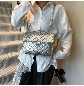 Macro view of metallic silver quilted texture and golden twist-lock on stylish tote bag