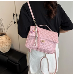 Close-up of pink quilted tote bag featuring a gold twist lock and a cute cartoon charm