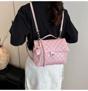 Detail shot of a pink quilted tote bag with a metal twist lock and cute charm accessory