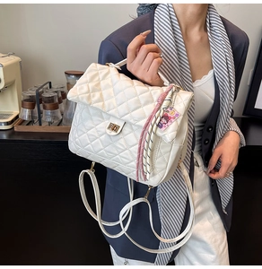 Close-up of white quilted tote bag featuring a gold twist lock and a decorative silk scarf