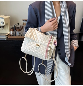Detail of white quilted tote bag with gold metal twist lock and a pink woven charm accessory